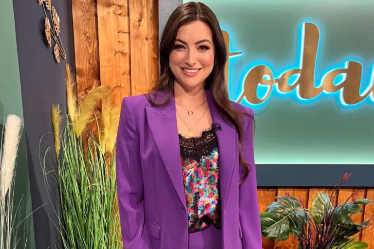 A photo of a woman in smart dress, standing in front of a screen featuring the word 'today'